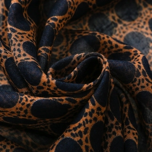 Detailed macro view of bohemian voile scarf fabric with dark blue and caramel leopard print