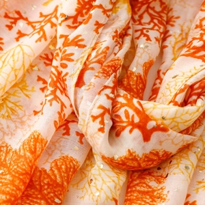 Close-up of coral patterns and gold foil details on a linen-touch summer scarf