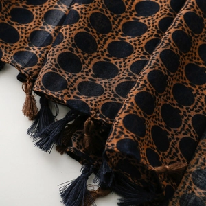 Detail of bohemian scarf fabric showing leopard dots pattern and bicolor tassels