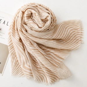 Detail of beige zebra striped scarf with fine fringe edges and lightweight texture