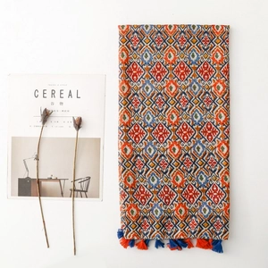 Bohemian geometric floral scarf with fringe detail on a minimalist white aesthetic backdrop