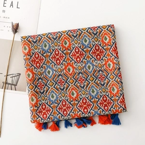 Detail of geometric ethnic scarf with vibrant floral patterns and orange-blue tassels