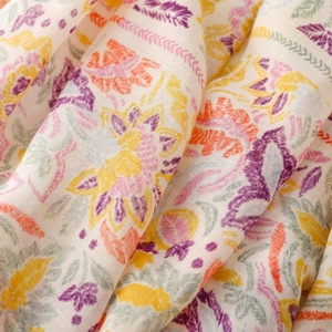 Macro shot of boho floral scarf showing purple and orange patterns on light fabric