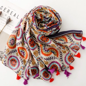 Détail d'une écharpe bohème à imprimé fleuri avec pompons et motifs géométriques ethniques