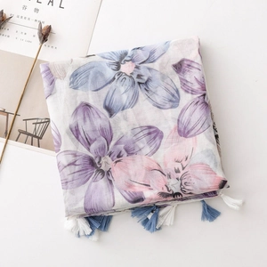 Detail of floral printed scarf with blue and white tassels on light voile fabric