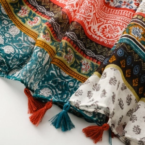 Detailed view of bohemian floral patterns and colorful fringe tassels on a cotton scarf