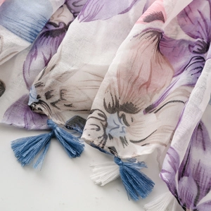 Detail of floral print scarf with blue and purple tassel fringe on textured fabric