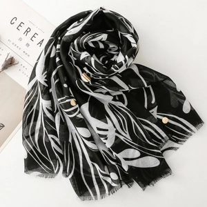Detail of black and white leaf print scarf with gold accents and frayed edges