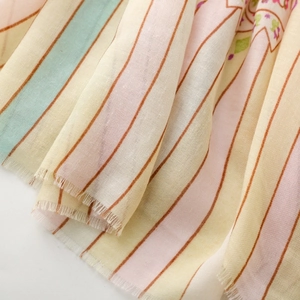 Detail of floral striped scarf with soft pastel tones and delicate fringe edges