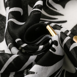 Macro detail of breathable black and white fabric with gold metallic aglet decoration