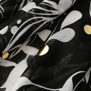 Macro shot of black scarf with white leaf prints and shimmering gold foil dot details