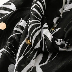 Detailed macro view of tropical leaf print on black fabric with gold sequin accents