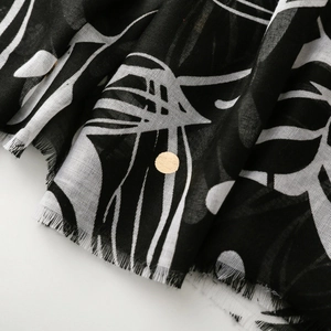 Macro view of black and white botanical print on lightweight scarf with fringe edges