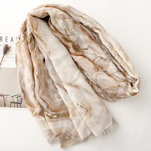 Detail of light beige scarf with gold foil marble texture and soft frayed edges