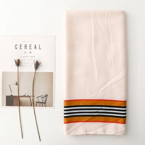 Detail showing beige linen texture scarf with colorful striped edges on a white background
