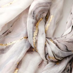 Detail of marble pattern fabric with luxury gold foil accents on a lightweight scarf
