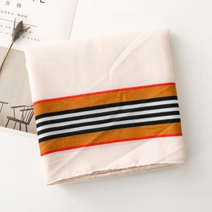 Detail of striped cotton-linen scarf with red trim beside a lifestyle magazine