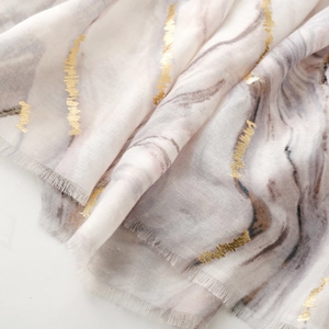 Close-up of marble print scarf with gold foil lines and soft frayed edge texture