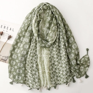 Detailed view of bohemian geometric star patterns and two-tone tassels on a green scarf