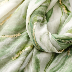 Detail of green and white cotton linen scarf featuring elegant gold foil ripple patterns