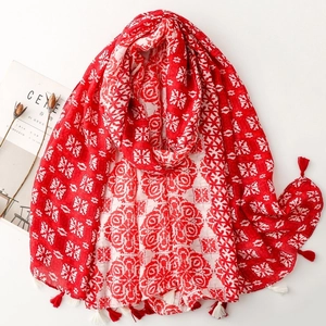 Close-up of geometric floral pattern scarf with red and white tassel fringe detail
