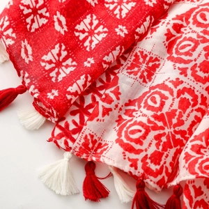 Detail of red and white geometric floral scarf with handmade tassels and woven texture