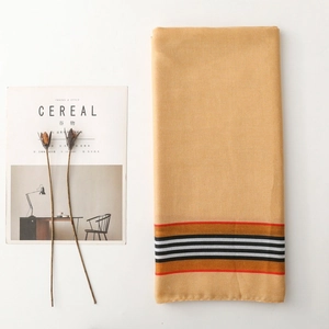 Detailed close-up of yellow striped cotton linen scarf with soft texture and chic fringe