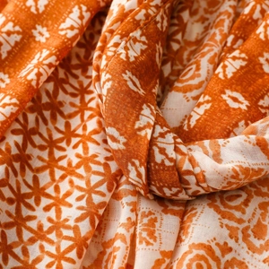 Detail of bohemian geometric pattern shawl with orange and beige linen-feel fabric