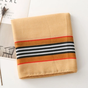 Detail of striped cotton-linen scarf showing thin orange and brown lines on ginger fabric