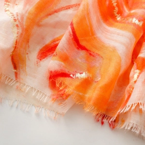 Detail of artistic gradient scarf with gold foil accents and frayed tassel edges