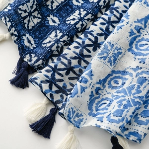 Macro detail of geometric print scarf showing linen-touch fabric and fringe tassels