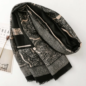 Detail view of paisley pattern scarf with geometric stripes and soft fringe edges