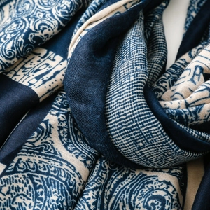 Detailed close-up of dark blue paisley and grid patterns on a linen-feel scarf fabric