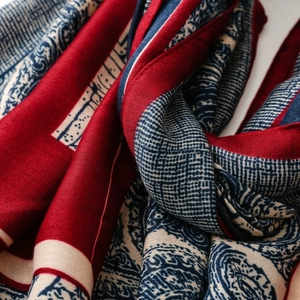 Detailed close-up of retro paisley and geometric patterns on a soft crimson pashmina shawl
