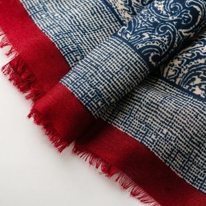Macro detail of retro paisley shawl showing blue geometric patterns and red fringe