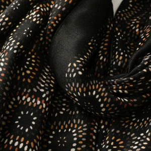 Macro detail of geometric kaleidoscope dots on soft black lightweight fabric shawl