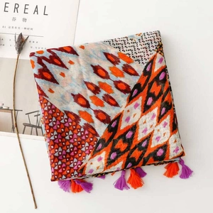 Detail of bohemian scarf with colorful geometric patterns and decorative dual-tone tassels