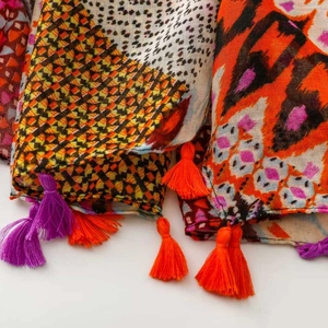 Detail view of colorful bohemian pattern scarf with vibrant orange and purple tassels