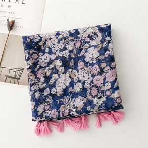 Dettaglio della sciarpa leggera a fiori blu con nappe rosa e motivi floreali dipinti