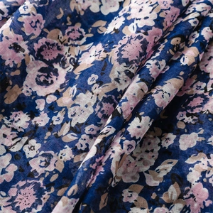 Dettaglio della sciarpa floreale blu che mostra la trama in cotone lino e fiori rosa