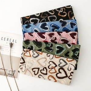 Flat lay of cotton linen scarves with gold heart prints in black, blue, and pink colors