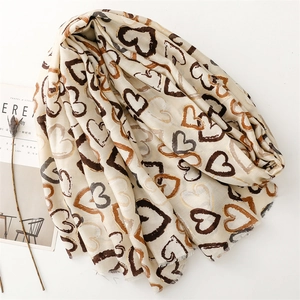 Detailed macro view of beige linen-touch scarf featuring hand-drawn heart prints and frayed edges