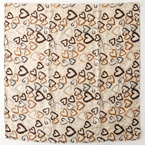 Detail shot of beige linen-feel scarf featuring multicolor heart patterns and raw edges