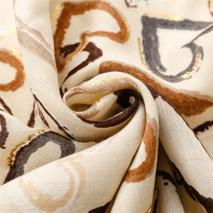 Macro detail of cream linen scarf featuring gold foil heart prints and woven texture