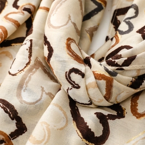 Detail of beige scarf featuring heart patterns with metallic gold foil stamping process