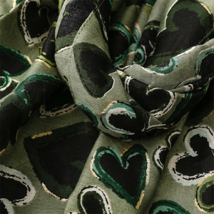 Macro detail of cotton linen scarf showing gold foil heart patterns and woven texture