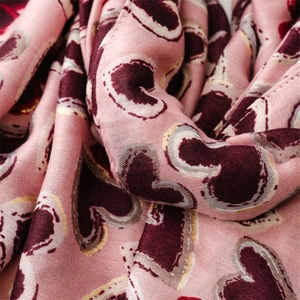 Detail view of pink cotton linen scarf featuring red heart prints with gold metallic edges