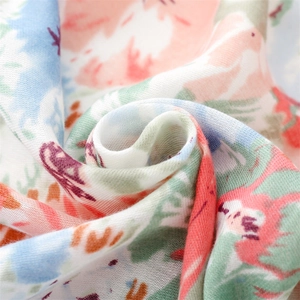 Close-up of soft floral cotton scarf fabric with pink rabbits and green leaves