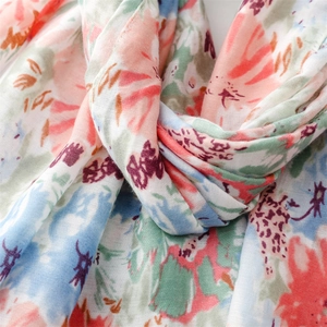 Detailed close-up of floral print scarf fabric showing soft cotton texture and tassels