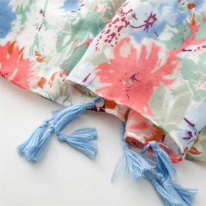Macro detail of soft blue and pink floral scarf showing texture and handmade tassels